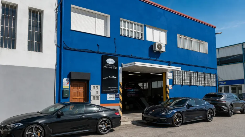 Imagen exterior de Carrocerías Poldo e Hijo, taller de chapa y pintura en Santander, con varios vehículos junto a la entrada del taller. La fotografía acompaña un artículo sobre taller concertado, libre elección de taller y reparación del coche tras un accidente.